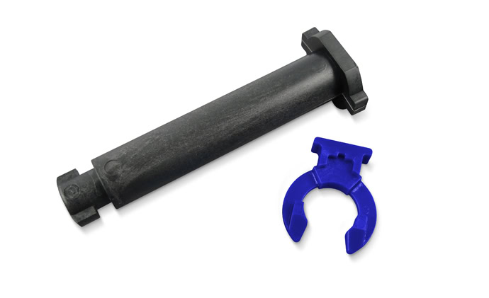 A black cylindrical tool with square ends lies next to a small blue plastic U-shaped clip, resembling a collector chain component, on a white background.