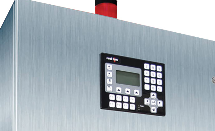 An industrial control panel with a stainless steel surface is shown. It features a digital display and a keypad with multiple buttons, including directional arrows and numeric keys.