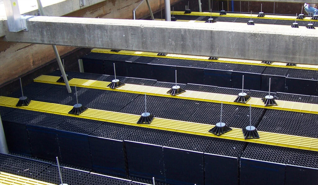 A photograph of a wastewater treatment tank shows multiple rows of black and yellow honeycomb-like panels supported by vertical metal rods. These AccuFAS panels are arranged in a grid pattern and are integral to the tank's Biological Treatment filtration system.