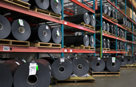 an image of warehouse shelves containing rolls of the Koroseal Perforated Plate Wrap from Brentwood Industries