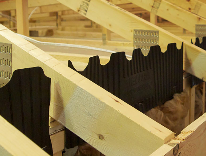 Detalle de las vigas de madera del tejado con los respiraderos de cumbrera accuvent instalados entre ellas. La imagen muestra la estructura del tejado y el sistema de ventilación del edificio.