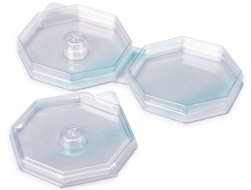 Transparent, plastic blister packaging with two octagonal compartments. Each compartment has a raised circular section in the center.