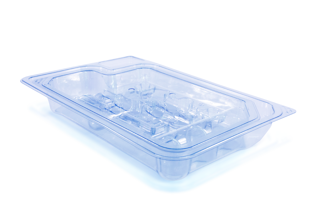 A transparent plastic tray with a fitted plastic cover, used for medical packaging, The tray has multiple compartments and is placed on a white surface with a slight blue hue in the background.