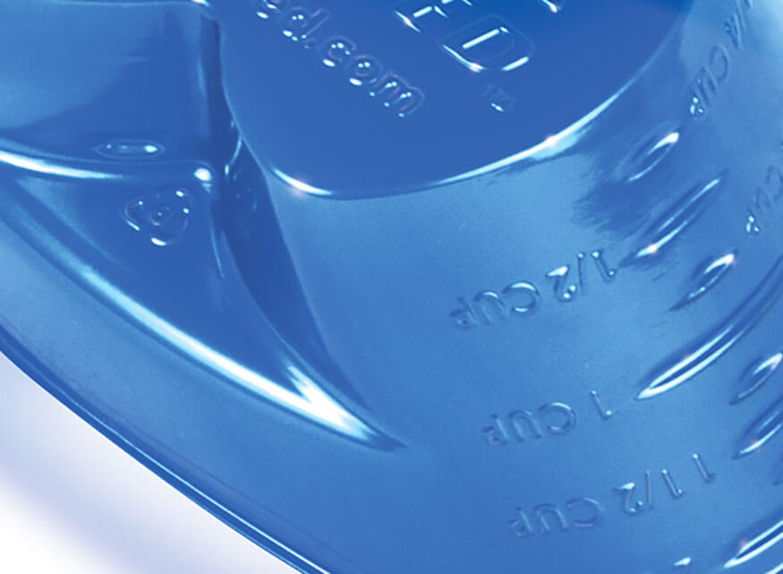 Close-up image of a blue measuring cup with embossed measurement markings showcasing its capabilities. The markings indicate volumes for 1/2 cup, 1 cup, and 1 1/2 cups.