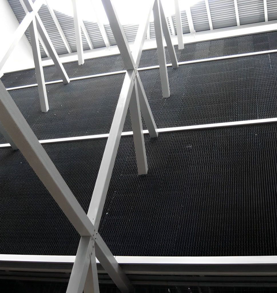 A view looking upward at metal beams and supports under a high ceiling with large skylights showcasing drift eliminators.