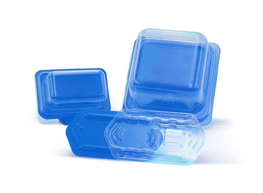 Blue plastic blister packs of various sizes are displayed against a plain white background. The healthcare packaging is arranged in a casual, overlapping manner, showcasing their transparent lids and blue bases.