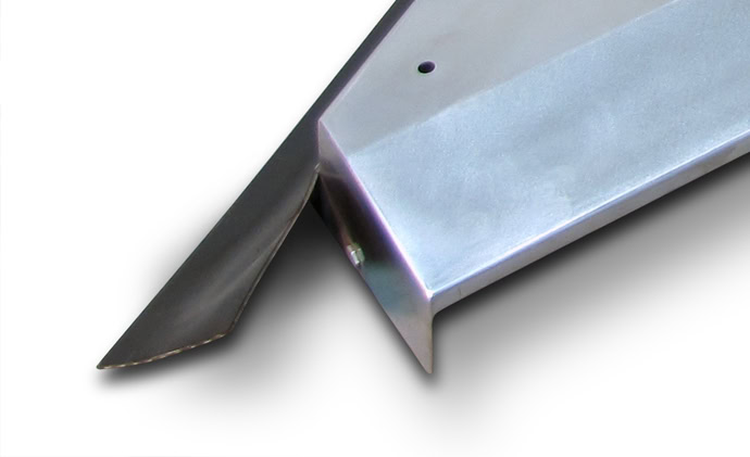 Close-up of two metal parts joined together, with one piece featuring a bend at an angle. The surfaces have a smooth, shiny finish, and a small hole is visible on one of the parts.