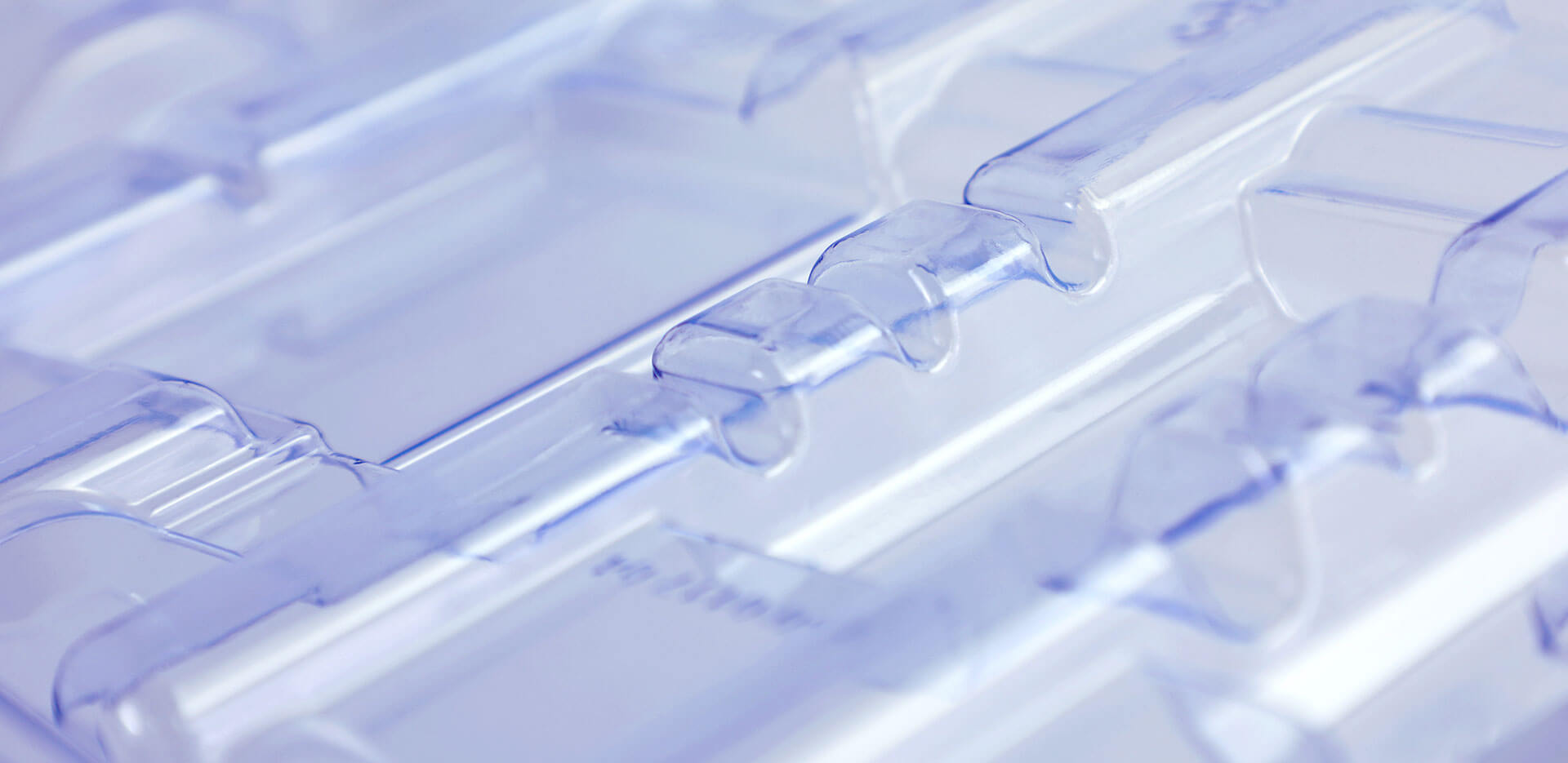 A close-up shot of transparent, plastic, clam-shell packaging with clean lines and edges. The focus on the smooth, clear material highlights its shape and structure.