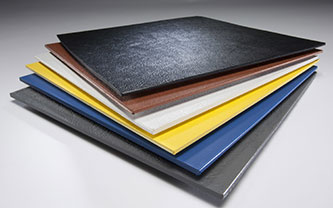 A stack of colored rigid plastic sheets, crafted from premium materials, is displayed with sheets in black, brown, white, yellow, blue, and gray layered from top to bottom on a smooth surface.