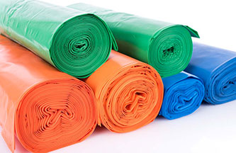 Six rolls of bags are displayed on a white background. Three rolls are green, two are orange, and one is blue. They are made out of LDPE plastic.