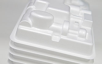 A stack of white foam trays, made from resilient materials, with compartments designed to hold different items.