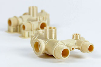 The image shows two complex, beige components with various cylindrical openings and threaded sections, placed on a light background.