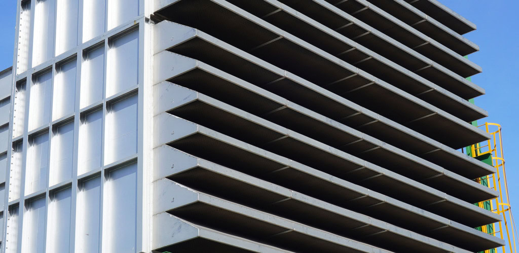 A close-up view of the side of an industrial-style building with multiple horizontal metal slats, creating a layered effect.