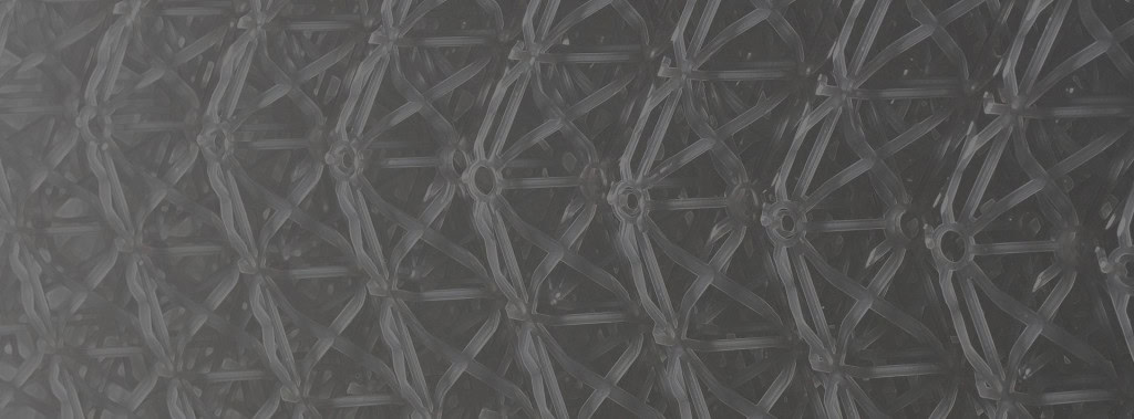 Close-up of an intricate black lattice structure featuring a repeating pattern of interconnected nodes and slender bars forming a web.