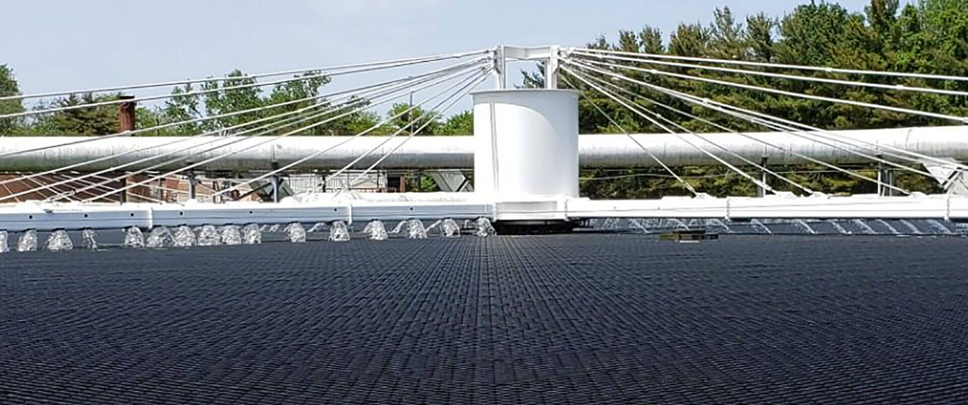 An advanced wastewater treatment facility featuring an array of circular aerators creating visible water currents on a large, grated platform.