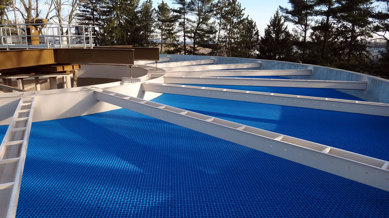 A large, circular water treatment facility with blue grates covering the surface.