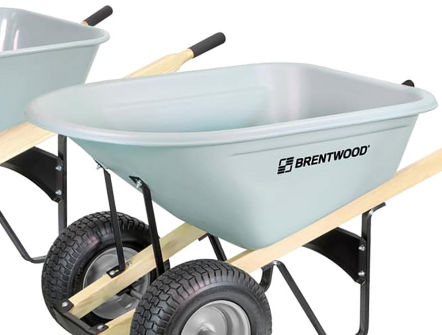 A light blue wheelbarrow with the brand name "Brentwood" printed on the side. It has a sturdy black metal frame and two large, rugged tires. Another similar wheelbarrow is partially visible in the background.