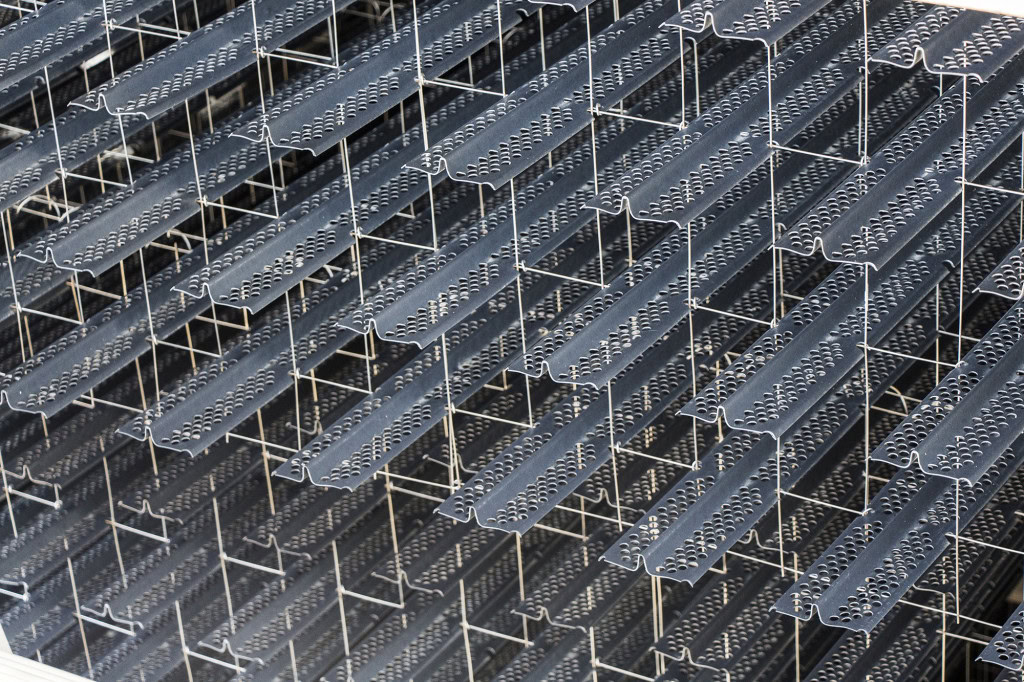 A close-up view of splash fills made of interlocking metal beams with perforated surfaces. The beams form a grid-like pattern.