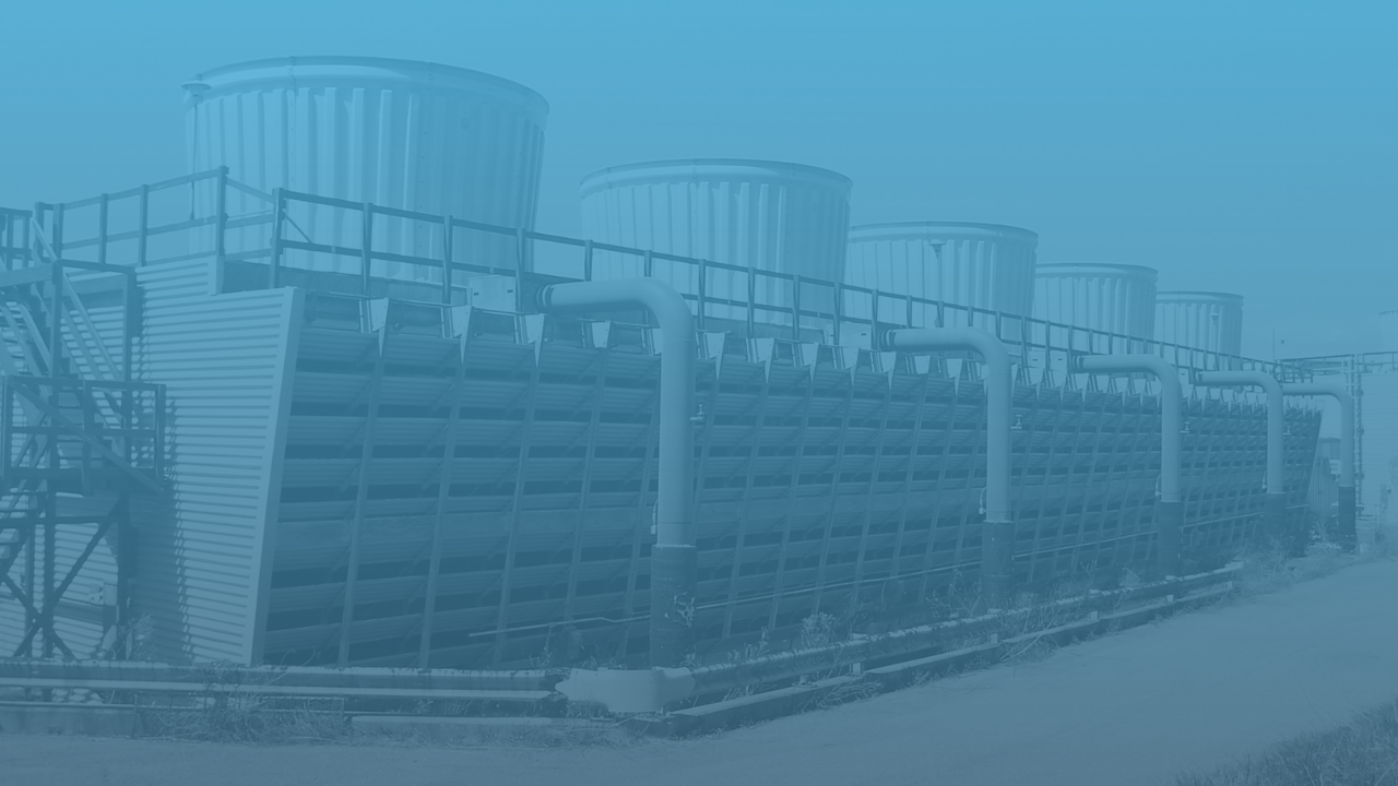 Large, industrial cooling towers lined up in a row, with a series of pipes connected to them.