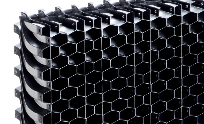 Primer plano de una estructura de panal de plástico negro formando un patrón en forma de rejilla. El diseño presenta celdas hexagonales apiladas en múltiples filas y columnas, proporcionando un marco resistente y ligero utilizado habitualmente en diversas aplicaciones de ingeniería como eliminador para gestionar el flujo de aire descendente.