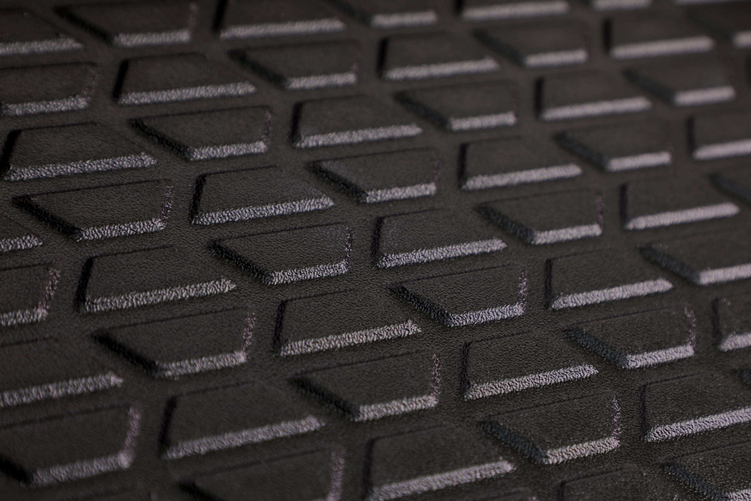 Close-up of a textured plastic surface featuring a geometric pattern of raised, shapes arranged in diagonal rows showcasing Brentwood's heavy gauge thermoforming abilities.